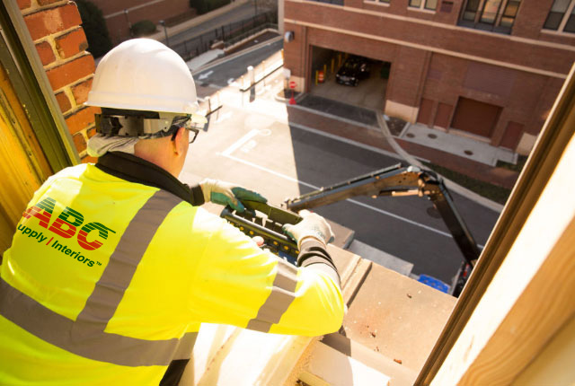 ABC Supply Interiors employee working on a window on an elevated floor in building under construction