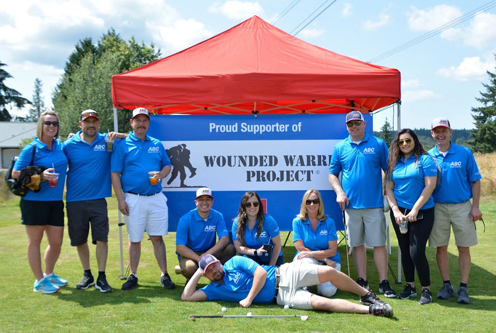 Group of ABC Supply Interior employees in front of Wounded Warrior Project banner